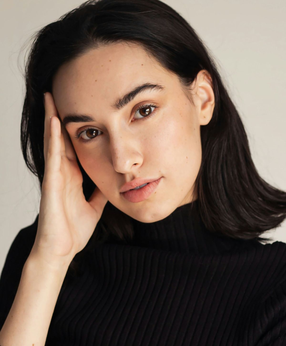 Woman touching her face, wearing a black sweater