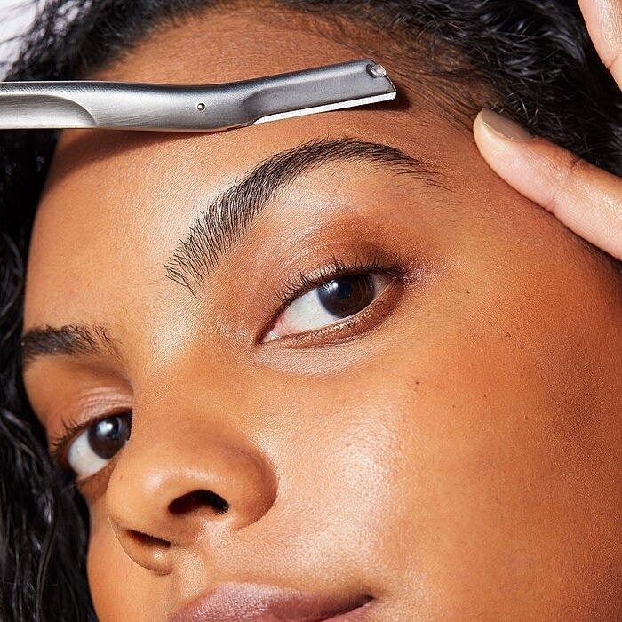 Smiling woman with curly hair and radiant skin.